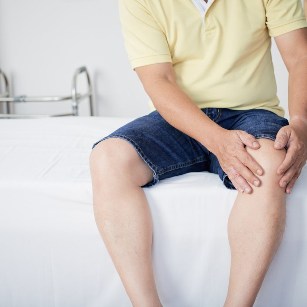 Crop man touching aching knee